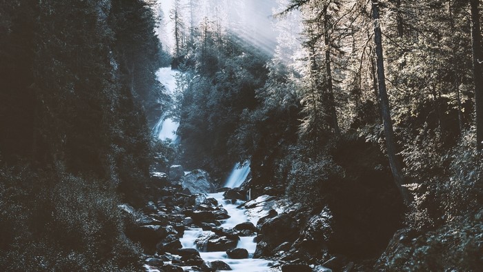 Waterfall in a dark forest with sunbeams