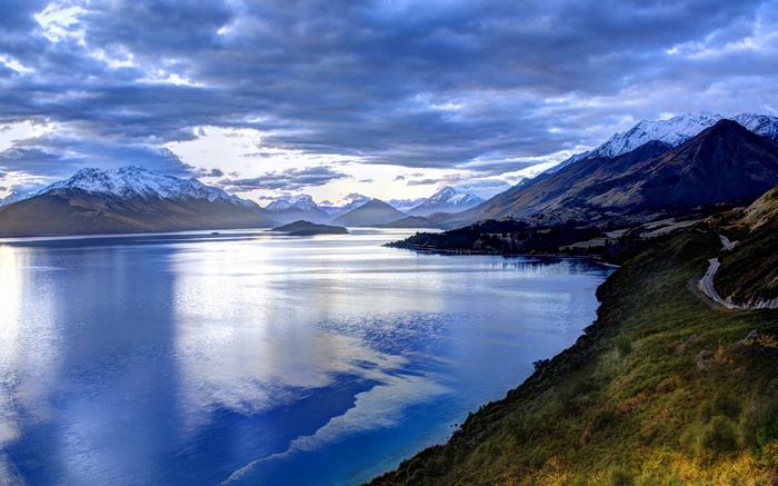 Snow-capped mountains reflected in a lake under a cloudy sky