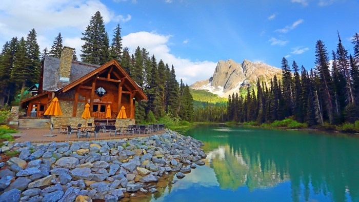 Wooden lodge by a turquoise lake with mountains