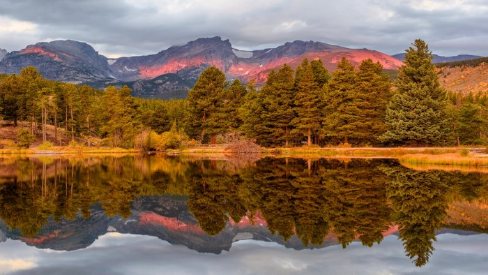 Mountain lake reflection with pine trees and autumn foliage