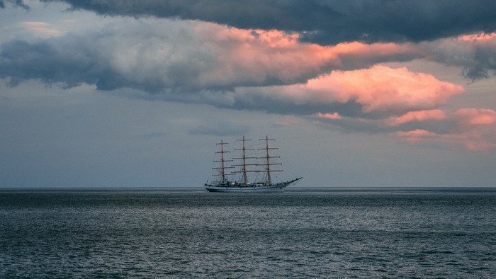 Tall ship sailing on the ocean at sunset