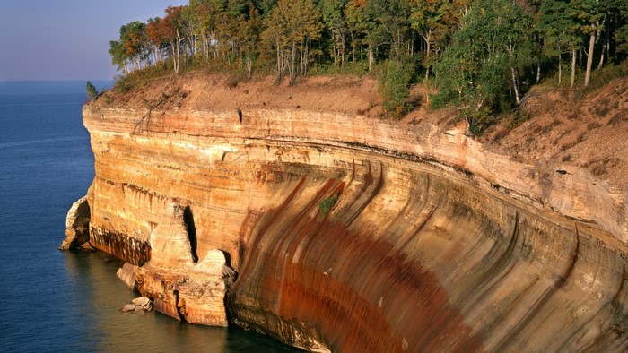 Steep cliff overlooking blue water with trees