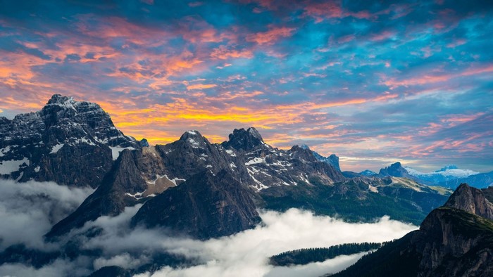 Sunset over snow-capped mountains with clouds