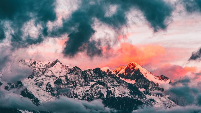 Sunset over snow-capped mountains with dramatic clouds