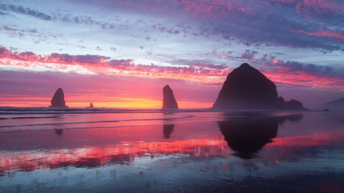 Sea stacks and colorful sunset reflection on beach