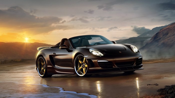 Brown Porsche convertible on a beach at sunset