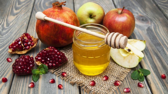 Pomegranates, apples, and honey on a wooden table
