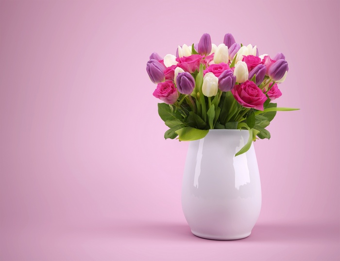 Bouquet of pink roses and purple and white tulips in a white vase