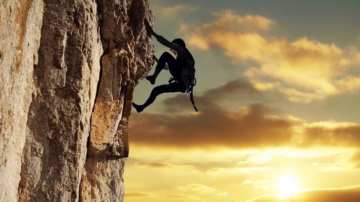 Silhouette of a climber on a rock face at sunset