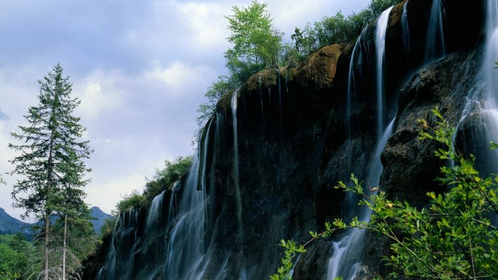 Mountain waterfall with trees and sky