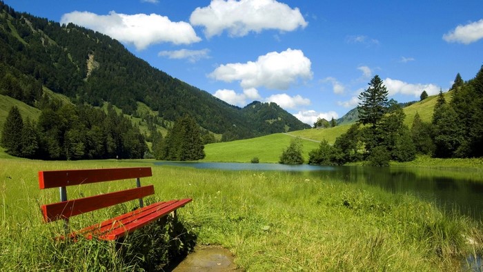 Red bench by a lake in the mountains