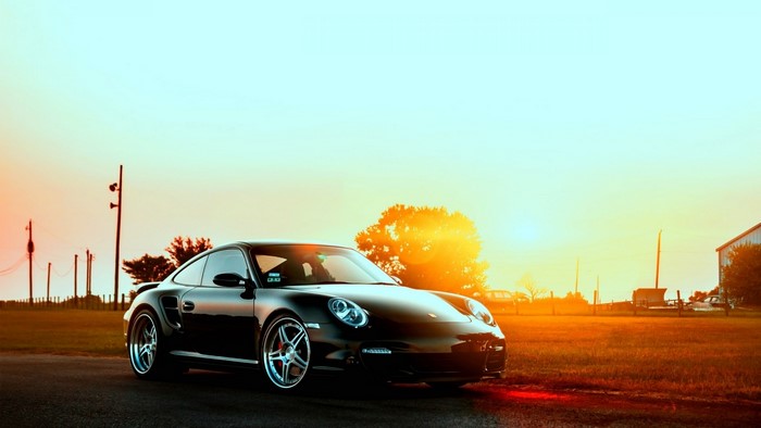 Black Porsche 997 on a road at sunset