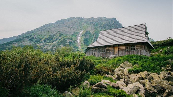 Wooden mountain cabin with rocky slope and green trees