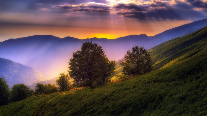 Sunset over misty mountains and green hills