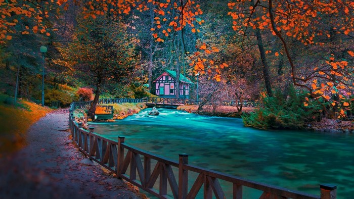Autumn park with a river and a small house