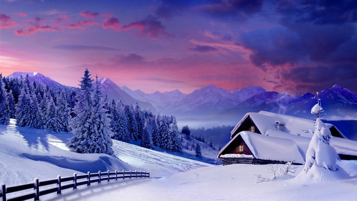 Snowy houses in a mountain landscape at sunset