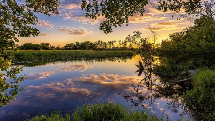 Sunset over a calm river with reflections