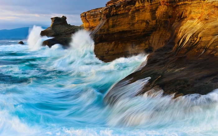 Waves crashing against rocky cliffs at sunset