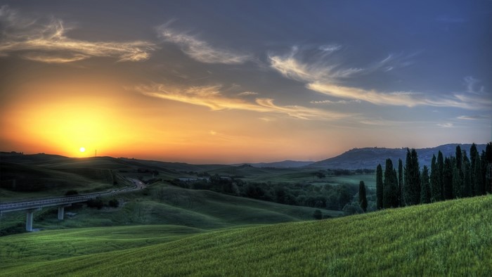 Tuscan landscape at sunset with rolling hills and cypress trees