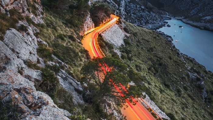 Mountain road with light trails overlooking a bay