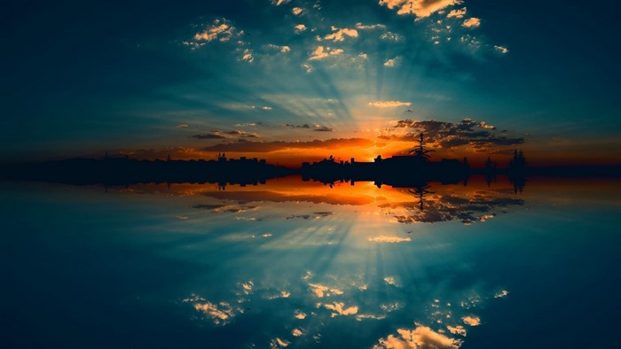 Sunset over city skyline reflected in water
