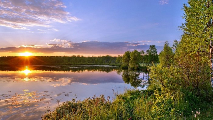 Sunset over a calm lake with trees and clouds