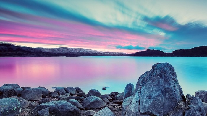 Pink and blue sunset over a rocky lake
