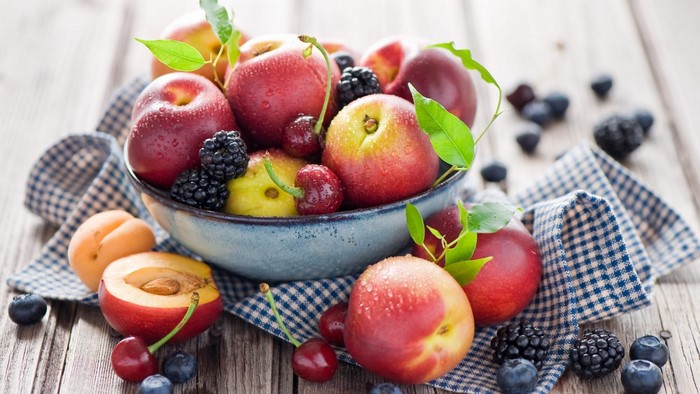 Bowl of fresh fruits and berries on a wooden table