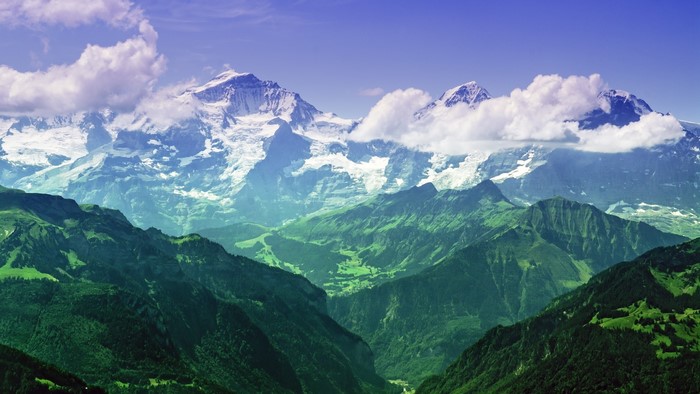 Snow-capped mountains and green valleys under a blue sky