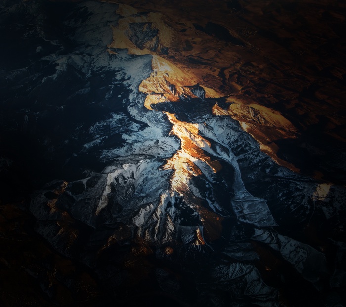 Aerial view of a snow-capped mountain range at sunset
