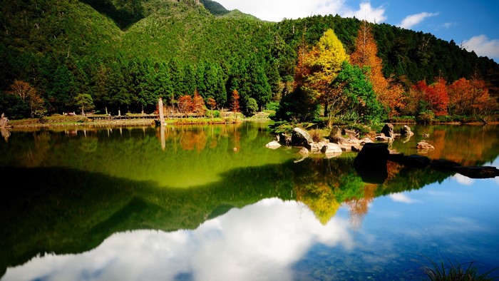 Colorful autumn trees reflected in a lake with mountains