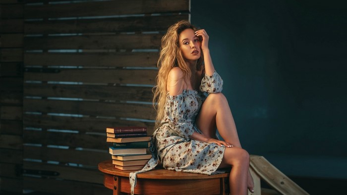 Blonde woman sitting on a table with books