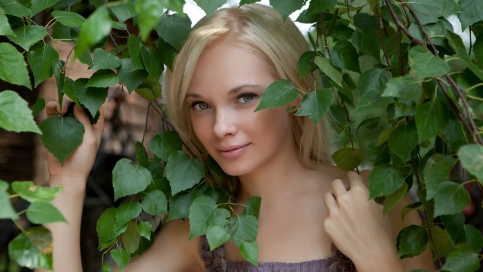 Blonde woman in green leaves