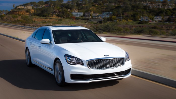 White Kia K900 driving on a road