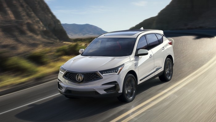 White Acura RDX driving on a winding road