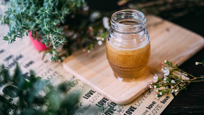 Jar of honey with herbs and flowers