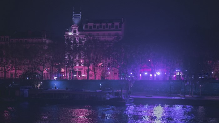 Cityscape at night with neon lights reflecting on water