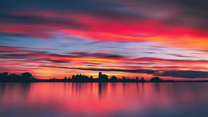 Sunset over a lake with a castle silhouette