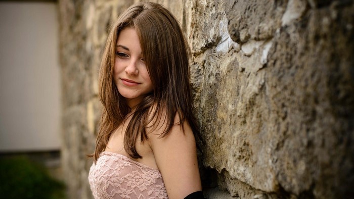 Girl leaning against a stone wall