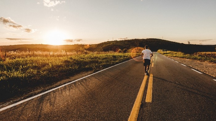 Man running on a road at sunset