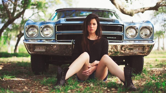 Woman sitting in front of a Chevrolet Chevelle