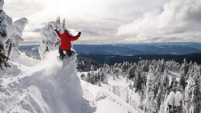 Snowboarder in Red Jacket Jumps Off Snowy Cliff