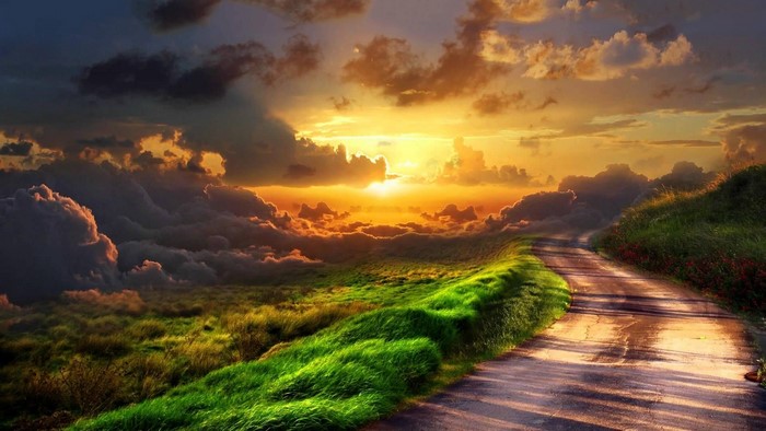 Sunset over a grassy hill with a road