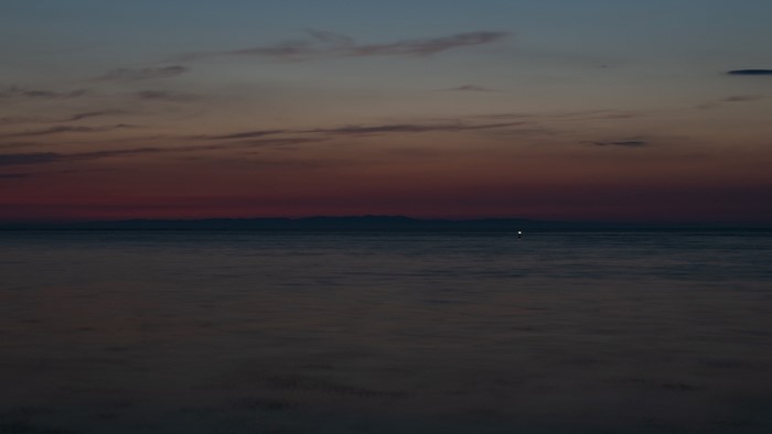 Sunset over the ocean with distant mountains