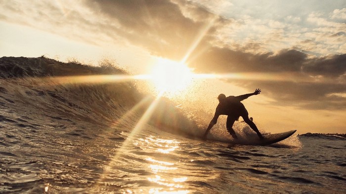 Surfer riding a wave at sunset