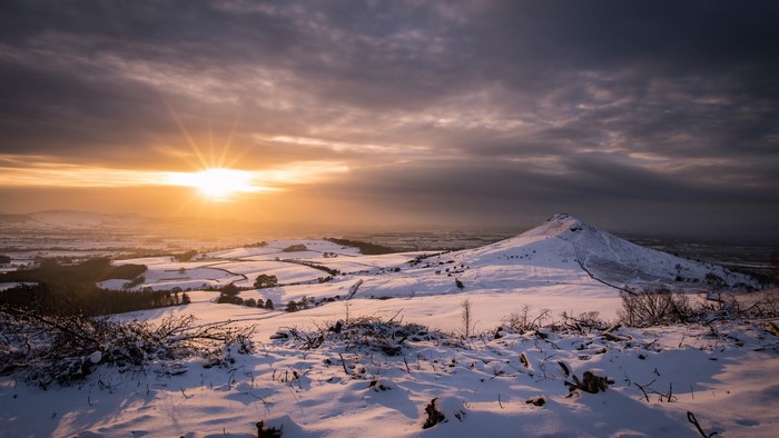 Snowy landscape with sunset over hills