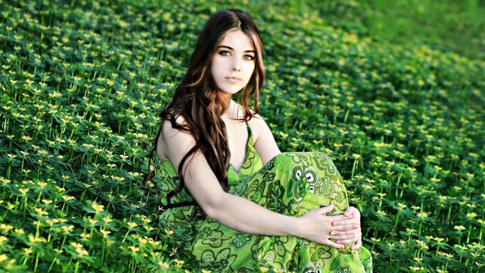 Young woman sitting in a field of green flowers