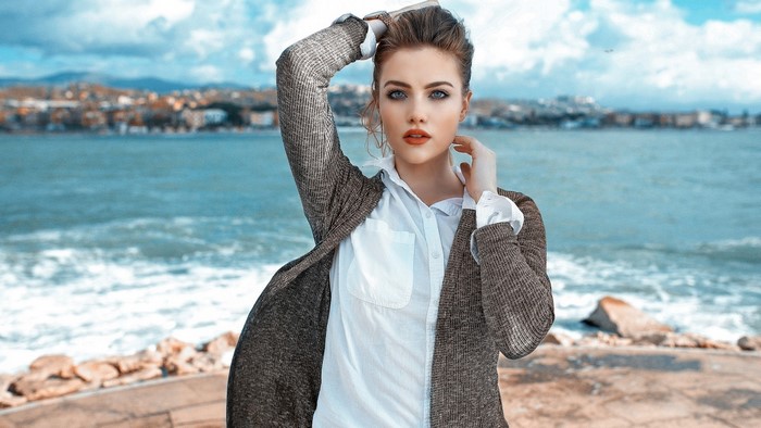 Woman in cardigan and white shirt by the sea