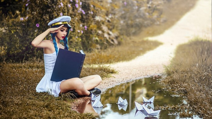 Model in captain's hat with book and paper boats