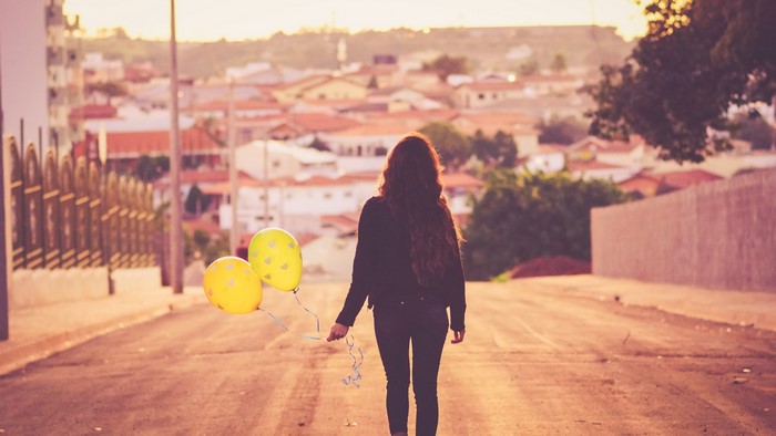 Girl with balloons walking away